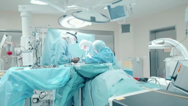 Sebészeti szoba egy csapat orvossal, akik egy beteget operálnak. — Stock videók