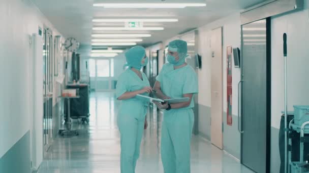 Dos doctores en uniforme quirúrgico están hablando en el pasillo — Vídeos de Stock