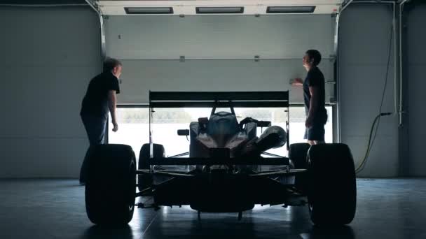 İki adam garajı açar ve bir yarış arabası sürer. — Stok video