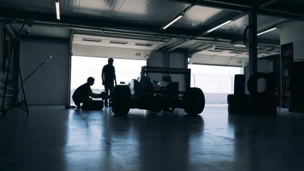 Οι υπηρέτες επισκευάζουν ένα αγωνιστικό αυτοκίνητο σε ένα γκαράζ. — Αρχείο Βίντεο
