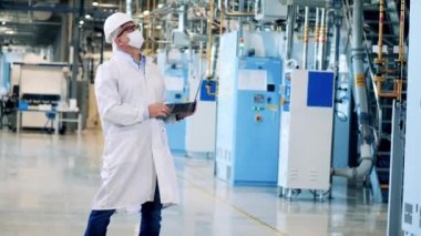 Laboratuvar önlüklü erkek mühendis fabrika inşaatlarını inceliyor.
