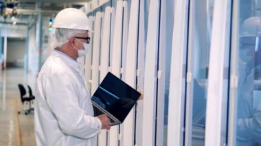 Dizüstü bilgisayarı olan erkek mühendis dolapları inceliyor.