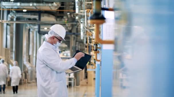 Ingénieur d'usine avec un ordinateur portable montre des données à son collègue — Video