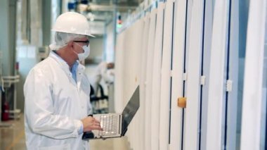 Erkek mühendis ekipman gözlemlerken dizüstü bilgisayarda daktilo kullanıyor