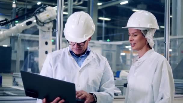 Dos ingenieros están hablando en la unidad de fábrica con máquinas de alta tecnología — Vídeo de stock