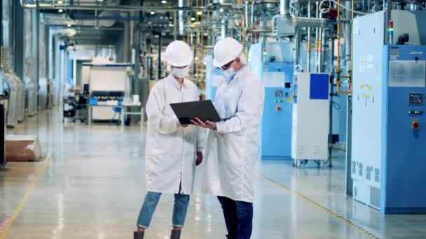 Unité d'usine avec deux ingénieurs en blouse de laboratoire se parlant — Video