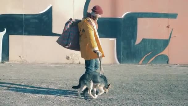 Un SDF conduit un chien le long de la rue de la ville — Video