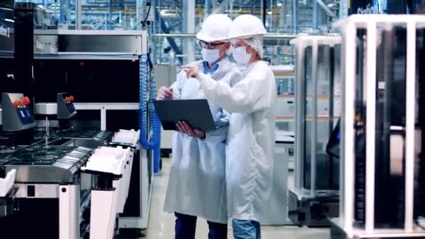 Два инженера завода наблюдают за производством солнечных панелей — стоковое видео