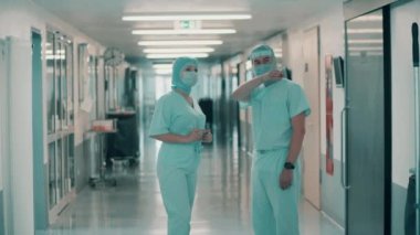 Cerrahi üniformalı doktorlar koridorda konuşuyorlar.