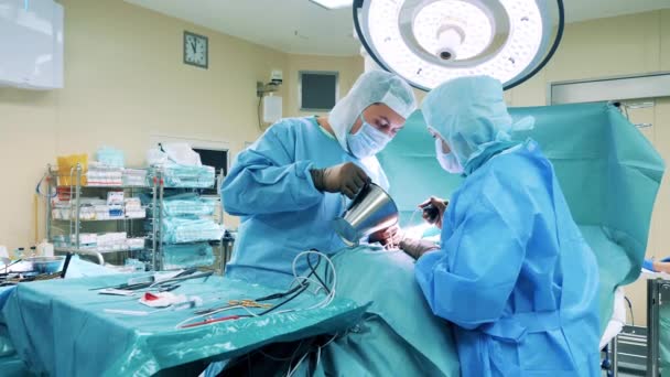 Los cirujanos están vertiendo líquido en la incisión durante la operación — Vídeos de Stock