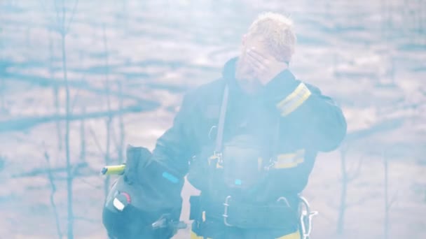 Strażak stoi w strefie pożaru lasu i patrzy w kamerę. — Wideo stockowe