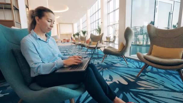 Egy nő mosolyog, miközben a laptopon dolgozik. — Stock videók