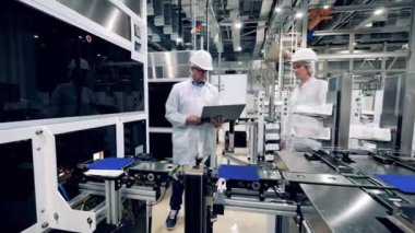Fabrika çalışanları güneş pillerinin yerini değiştiren bir taşıyıcıyı izliyor.