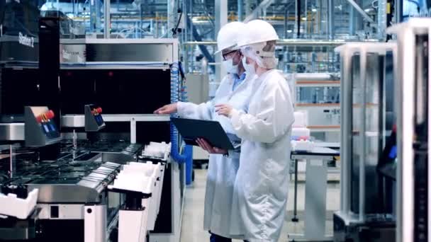 Dois especialistas em máscaras faciais estão assistindo a fabricação de células solares — Vídeo de Stock