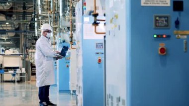 Bilgisayarlı bir fabrika çalışanı kabine panelini yönetiyor.