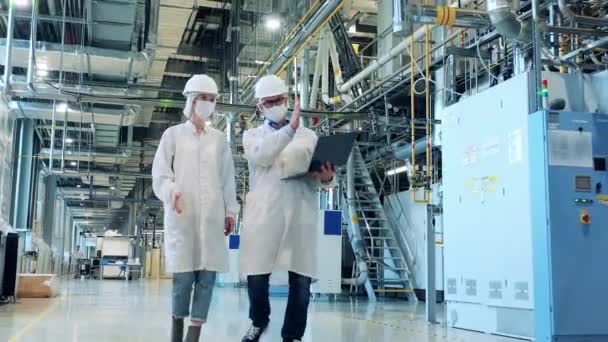 Dos empleados en batas de laboratorio están observando tuberías de fábrica — Vídeo de stock