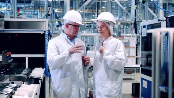 Сотрудники в лабораторных халатах разговаривают на заводе солнечных батарей — стоковое видео