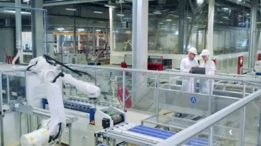 Bir robot güneş modüllerini iki uzmanın gözetiminde yeniden yerleştiriyor.