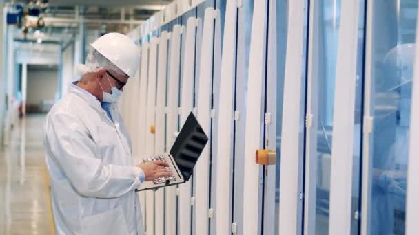 Male specialist with a laptop is inspecting factory cabinets — 图库视频影像