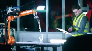 Güvenlik görevlisi erkek mühendis bir robot mekanizması üzerinde çalışıyor.