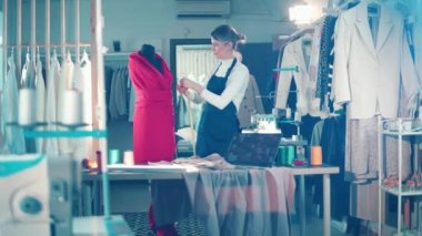 A seamstress is taking measurements of a dress