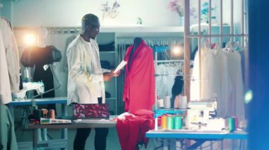African tailor is looking at a dress and its sketch