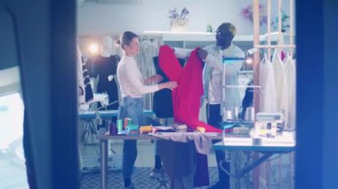 African tailor and a seamstress are wrapping fabric around the dummy