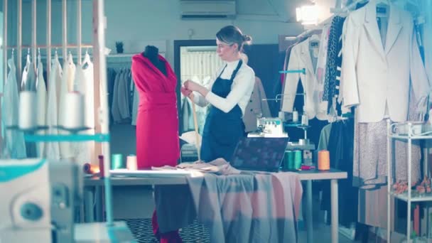 A seamstress is taking measurements of a dress — Stockvideo
