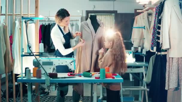 Seamstress and a girl are talking measurements of clothes — Stockvideo