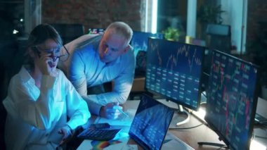 A man and a woman are monitoring stock data on the computers. Teamwork concept.
