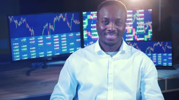 African-american stockbroker is smiling near trade rates monitors. — стоковое видео