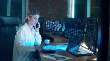 Financial, investment, business concept. Female stockbroker is talking on the phone while monitoring data