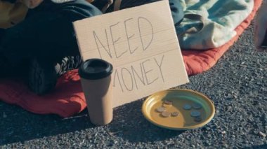 Coins are getting thrown into beggars plate