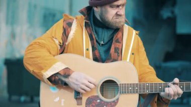 A poor man is playing the guitar in the street