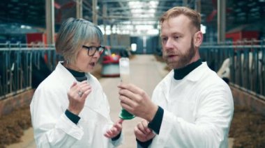 Two farm specialists are discussing a sample of raw milk
