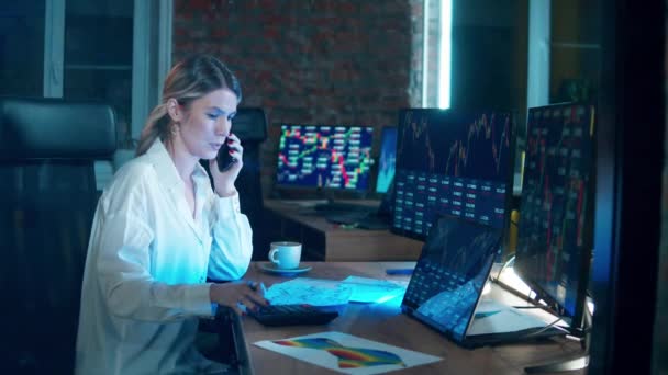 Financial, investment, business concept. Female stockbroker is talking on the phone while monitoring data — Stockvideo