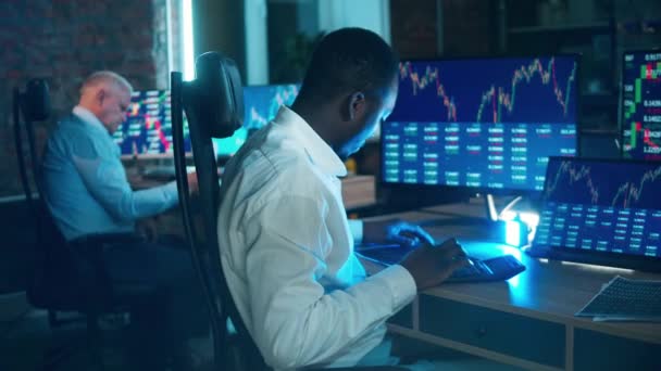 African stockbroker is calculating stock rates at his desk. Businessman trader, broker concept. — Vídeo de Stock
