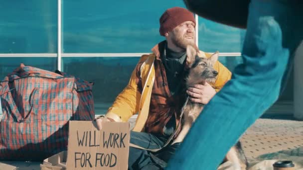 A beggar is sitting on the ground with his dog — Stockvideo