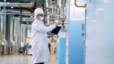 Male factory inspector with a laptop is operating control panels