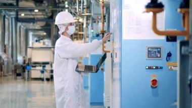 Female engineer is operating control panels of the factory cabinets