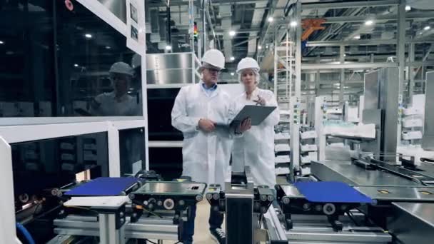 Two experts are observing robotized conveyor with solar cells — Video