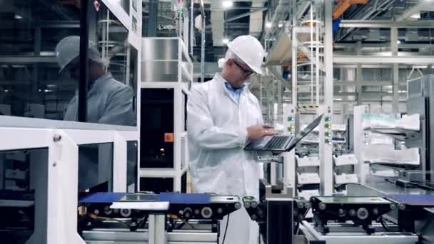 Factory inspector with a laptop is observing production of solar cells — Vídeo de Stock