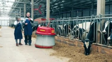 Tarım robotu ve iki çalışanı olan çiftlik hayvanları çiftliği.