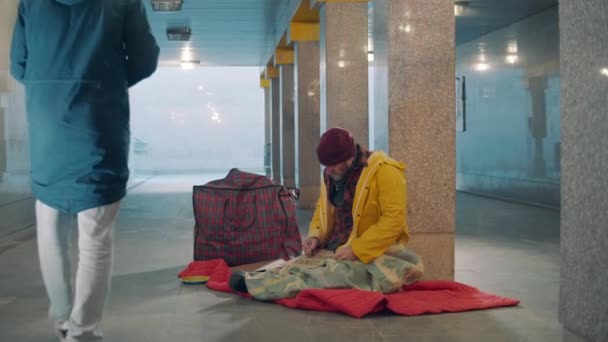 Een voorbijganger geeft aalmoezen aan een dakloze. — Stockvideo