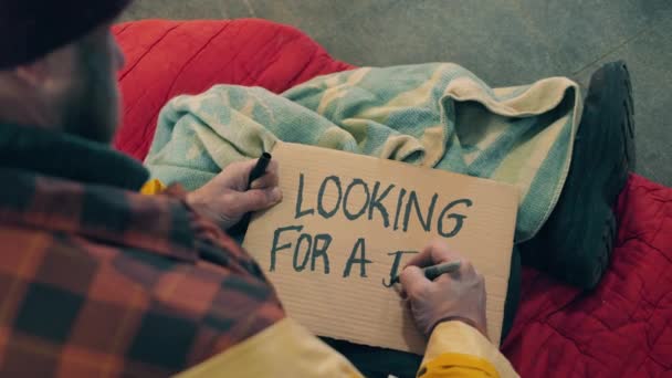 En tiggare skriver och söker jobb på en tallrik. — Stockvideo