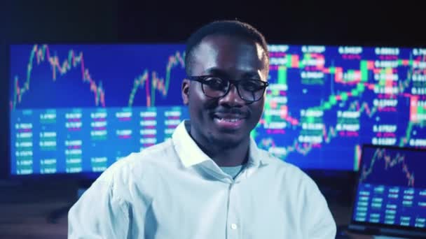 Afrikansk börsmäklare ler bredvid datorskärmar — Stockvideo