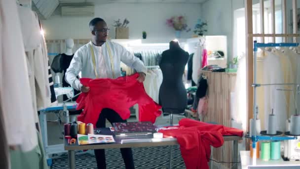 African tailor is wrapping red fabric around the dummy — Stock Video
