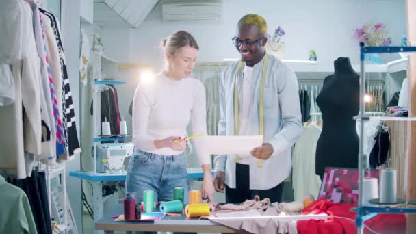 Zwei Schneiderinnen diskutieren in der Werkstatt eine Zeichnung — Stockvideo