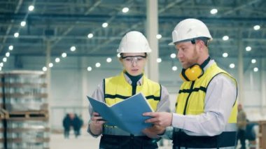 Fabrika işçileri raporu birlikte inceliyorlar. Modern fabrika, endüstriyel fabrikada çalışan mühendisler..