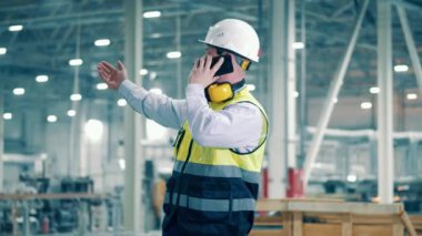 Fabrika işçisi, endüstriyel, teknoloji, üretim konsepti. Erkek işçi telefonda konuşuyor ve yol tarifi veriyor.